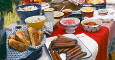 a table full of food including hot dogs, salads and other foods on it