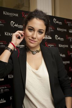 a woman standing in front of a red carpet talking on a cell phone and wearing a black blazer