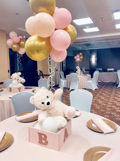 a teddy bear sitting in a box on top of a table with balloons and plates