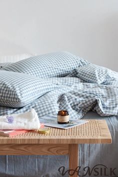 an unmade bed with blue gingham comforter and pillows on the side