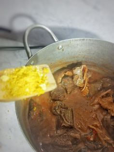 a pot full of stew with a wooden spoon