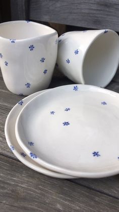 three white dishes sitting on top of a wooden table covered in blue flowered designs