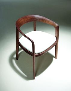 a wooden chair with a white cushion on the back and armrests that are bent to one side