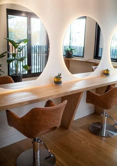 three round mirrors are on the wall above a table with chairs and stools in front of it