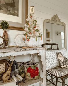 a white christmas tree sitting on top of a table next to a chair and mirror