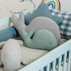 there is a stuffed whale in the crib next to some pillows and other toys