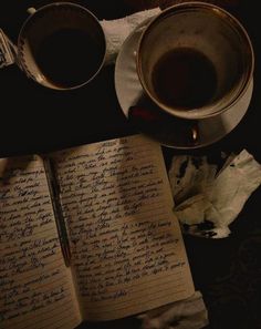 two cups of coffee are next to an open notebook