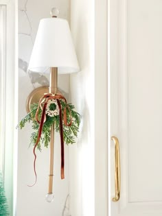 a christmas wreath hanging from the side of a white wall next to a light fixture