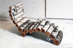 a chair made out of logs sitting on top of a floor next to a brick wall