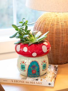 a potted plant sitting on top of a book next to a lamp