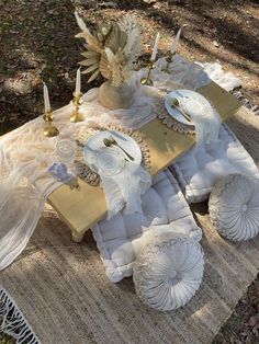 a table set up with plates and napkins on top of it in the woods