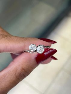 a woman's hand with red nail polish and two diamond rings on her finger