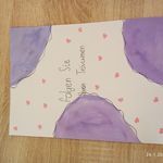 a purple and white greeting card on a wooden surface with hearts in the background,