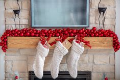 two stockings hanging from a mantel decorated with red balls