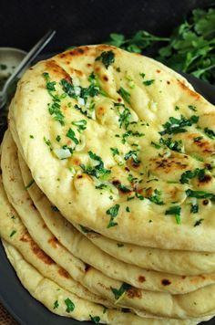 a stack of pita bread sitting on top of a black plate