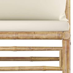 an upholstered bench made out of bamboo with white cushions on the seat and back