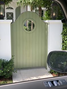 a car is parked in front of a house with a green gate and round window