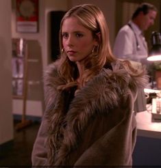 a woman in a fur coat standing at a counter