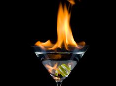 a martini glass with flames in it on a black background and the image appears to be burning