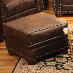 a brown leather chair sitting on top of a wooden floor next to a rug and two chairs