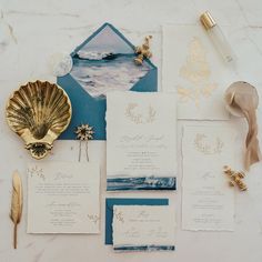 the wedding stationery is laid out on top of the table with gold and blue accents