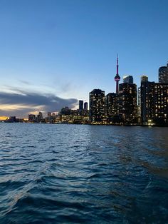 the city skyline is lit up at night as seen from across the water in toronto, canada