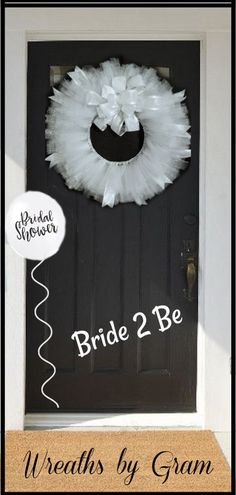 a black door with a white wreath on it and the words bride 2 be written below