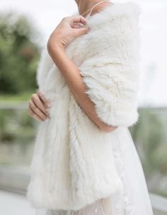 a woman wearing a white fur vest and wedding dress is holding her hand on her shoulder