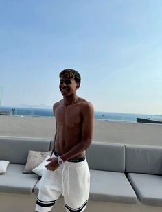 a shirtless man standing on the deck of a boat in front of the ocean