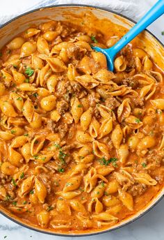 creamy beef and shells in a skillet with a ladle full of pasta sauce