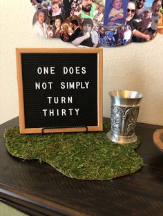 a sign that says one does not simply turn thirty on top of a moss covered table