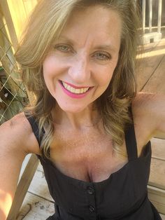 a woman with very large breast posing for the camera while wearing a black dress and smiling