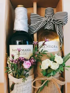 two bottles of wine and some flowers are in a box with twine ribbons on it