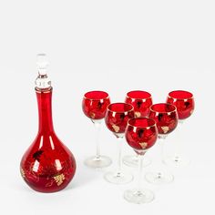 red wine glasses and a bottle with gold designs on them sitting next to each other