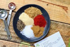 an assortment of spices on a plate next to a notepad and measuring spoons