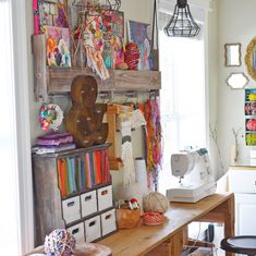 a sewing room with lots of crafting supplies on the desk and shelves above it