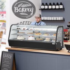 a man behind the counter of a bakery