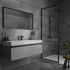 a modern bathroom with black and white tile on the walls, floor, and shower