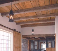 an open living room with wood paneling and exposed ceiling lights hanging from the rafters