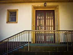 an old building with a door and some stairs in front of it, next to a set of steps that lead up to the second floor