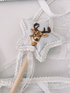 a deer head is on the back of a white star shaped pillow with a wooden stick