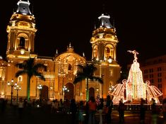 people are standing in front of a large building with christmas lights on it's sides