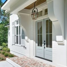 a white house with two doors and brick walkway