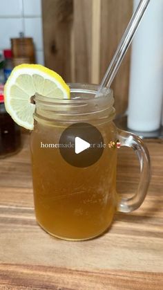 a mason jar filled with lemonade on top of a wooden table next to a cup