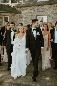 a bride and groom walking with their wedding party