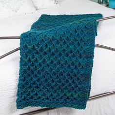 a crocheted blanket sitting on top of a bed next to a night stand