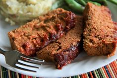 a white plate topped with meatloaf next to mashed potatoes and green beans