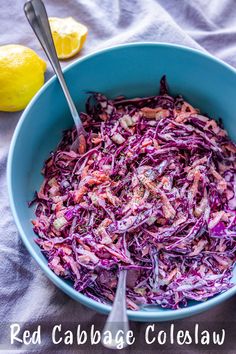 red cabbage coleslaw in a blue bowl with two lemons on the side