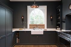 a kitchen with black cabinets and white counter tops, an oven, dishwasher and sink