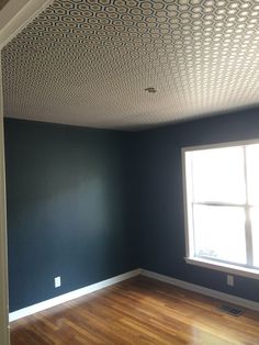 an empty room with blue walls and wood flooring in the foreground is a window